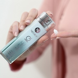 Image of a woman dispensing Neora Age IQ Day Cream in her hand.